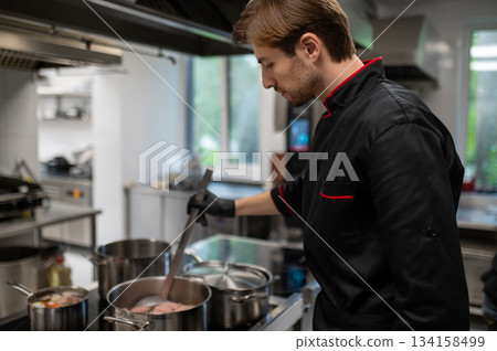 Chef in uniform working in kitchen interior Chef in uniform working in kitchen interior 134158499