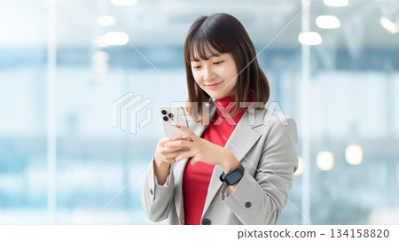 使用智慧型手機的微笑的女人/女商人 使用智慧型手機的微笑的女人/女商人 134158820