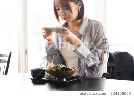 Woman taking a meal with a smartphone Woman taking a meal with a smartphone 134159060