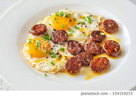 Hearty fried eggs served with caramelized chorizo slices and fresh scallion garnish Hearty fried eggs served with caramelized chorizo slices and fresh scallion garnish 134159255