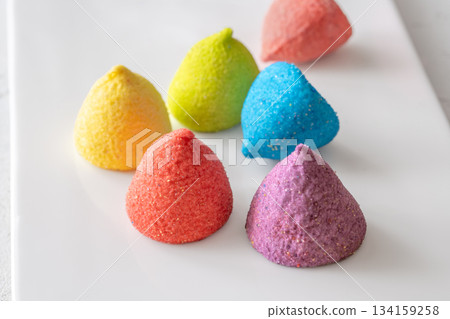 Colorful sugar-coated marshmallow pyramid candies sparkling on clean white rectangular platter Colorful sugar-coated marshmallow pyramid candies sparkling on clean white rectangular platter 134159258