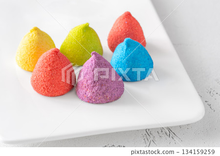 Colorful sugar-coated marshmallow pyramid candies sparkling on clean white rectangular platter Colorful sugar-coated marshmallow pyramid candies sparkling on clean white rectangular platter 134159259