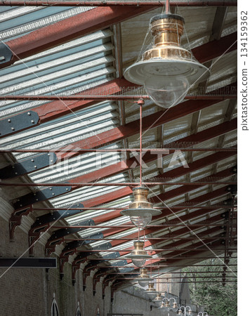 A vintage copper ceiling light fixture with a glass globe shade hangs from a white ceiling and Wooden beams. A vintage copper ceiling light fixture with a glass globe shade hangs from a white ceiling and Wooden beams. 134159362