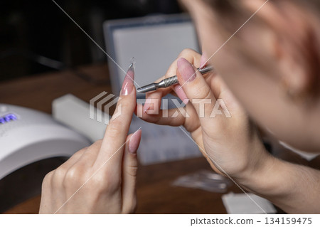 Woman doing a complex manicure by oneself, applying nail extension gel on upper forms, showcasing DIY beauty and personal care routine Woman doing a complex manicure by oneself, applying nail extension gel on upper forms, showcasing DIY beauty and personal care routine 134159475