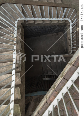 Upside view of The old stone spiral staircase with iron railing into Basement. 134159580