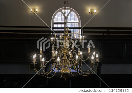 Beautiful view of Chandelier hanging from the ceiling with glass windows in the background of The Church of King Charles the Martyr. Beautiful view of Chandelier hanging from the ceiling with glass windows in the background of The Church of King Charles the Martyr. 134159585