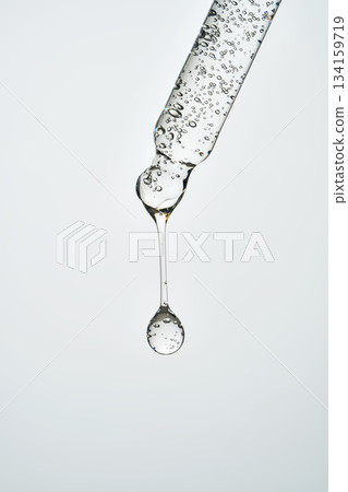 Pipette dripping transparent serum creating a perfect drop 134159719