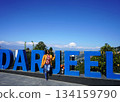 Woman Posing by Large Blue Darjeeling Sign under Clear Sky at Batasia Loop 134159790