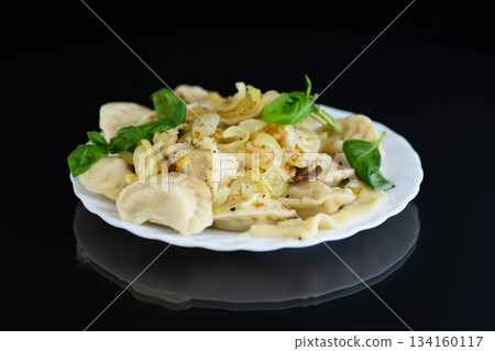 A plate of dumplings decorated with fried onions and herbs A plate of dumplings decorated with fried onions and herbs 134160117