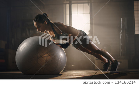 Athletic woman performs push-ups on exercise ball in gym during morning workout session Athletic woman performs push-ups on exercise ball in gym during morning workout session 134160214