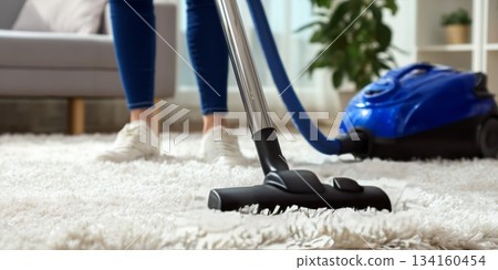 Woman using vacuum cleaner on plush carpet in modern living room with cozy atmosphere Woman using vacuum cleaner on plush carpet in modern living room with cozy atmosphere 134160454