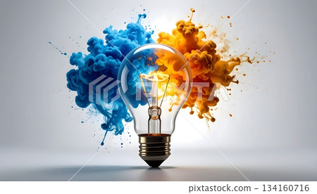 Creative concept of a light bulb with vibrant blue and orange powder explosions symbolizing innovation, imagination and the clash of contrasting ideas 134160716