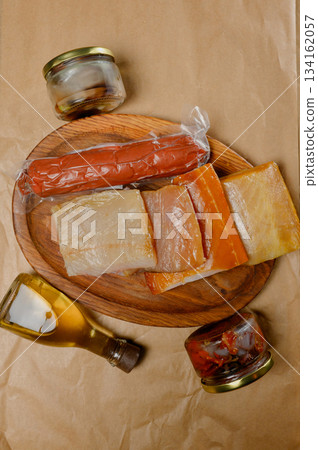 Smoked fish pieces and dry-cured sausage with butter on craft paper. Smoked fish pieces and dry-cured sausage with butter on craft paper. 134162057
