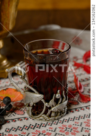 Close-up of a glass of hot tea with berries in a metal cup holder Close-up of a glass of hot tea with berries in a metal cup holder 134162062