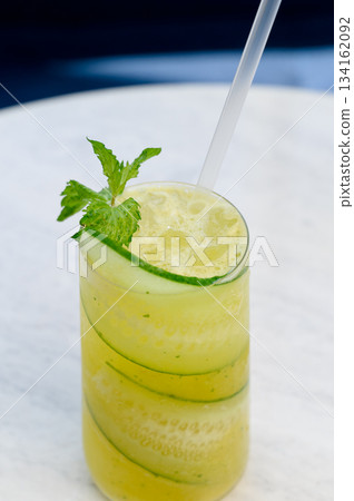 Close-up of a glass of summer drink with cucumber, mint and a straw. 134162092