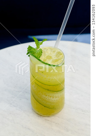 Close-up of a glass of summer drink with cucumber, mint and a straw. 134162093