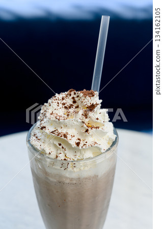 Chocolate milkshake with whipped cream and cocoa chips in a tall glass. Chocolate milkshake with whipped cream and cocoa chips in a tall glass. 134162105