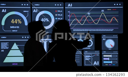 AI Using. Silhouetted analysts interact with a large AI data. AI Display charts graphs and analytics. Business team using futuristic AI interface visuals data. Technology with biz insights and ai data 134162293