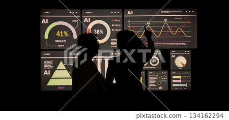 AI Using. Silhouetted analysts interact with a large AI data. AI Display charts graphs and analytics. Business team using futuristic AI interface visuals data. Technology with biz insights and ai data 134162294