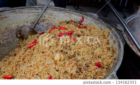 Steaming flavorful chili rice, Vendor preparing vibrant spicy rice dish, Colorful rice with chilies and garlic at festival, Aromatic spicy pilaf featuring whole chilies and garlic at local food Steaming flavorful chili rice, Vendor preparing vibrant spicy rice dish, Colorful rice with chilies and garlic at festival, Aromatic spicy pilaf featuring whole chilies and garlic at local food 134162351