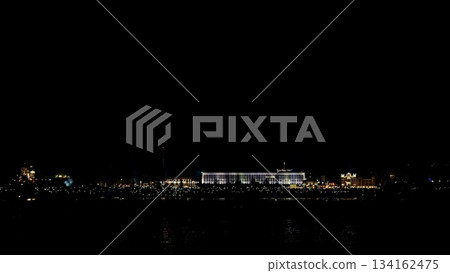 serene harbor skyline at night, dimly lit waterfront building reflects faint lights on calm water, distant structures under wide black sky, moody minimalist atmosphere with subtle amber glow serene harbor skyline at night, dimly lit waterfront building reflects faint lights on calm water, distant structures under wide black sky, moody minimalist atmosphere with subtle amber glow 134162475
