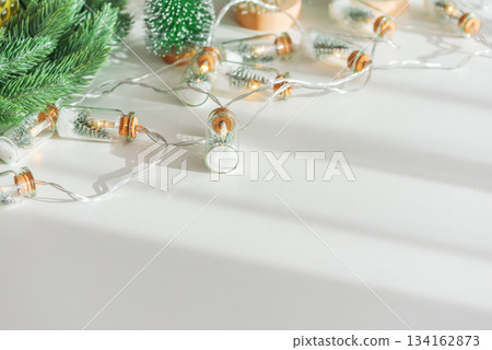 Miniature Christmas Tree Bottle Lights with Snow and Small Pine Trees on White Background 134162873