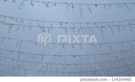Rows of stretched light cables and disconnected garland against a clear blue sky outdoor urban holiday decoration Rows of stretched light cables and disconnected garland against a clear blue sky outdoor urban holiday decoration 134164465