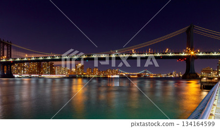 Night view of Manhattan Bridge with city lights reflecting on water Night view of Manhattan Bridge with city lights reflecting on water 134164599
