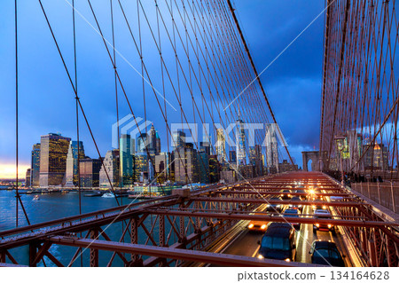 Brooklyn Bridge connects Manhattan Brooklyn with NY city lights traffic at dusk 134164628
