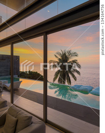 View from luxury villa at sunset, sun loungers for sunbathing, umbrellas from the sun, pillows for swimming in the pool, palm tree on background 134164756