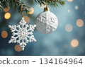 White christmas ornament and snowflake hanging from a fir tree branch 134164964