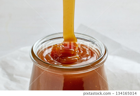 freshly cooked homemade caramel sauce pouring in jar 134165014