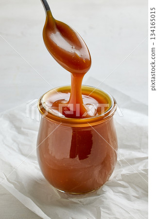freshly cooked homemade caramel sauce pouring in jar 134165015