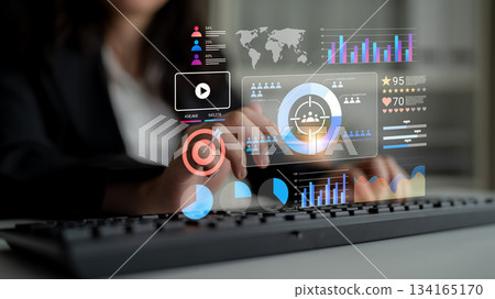 Business professional interacting with digital data visualization and analytics on futuristic interface while working on a keyboard in a modern office environment Gantry 134165170