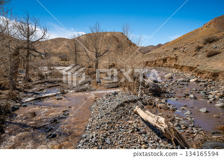 Mountain stream at the foot of the Red Mountains Mars Altai Russia. Natural watercourse in a unique colorful geological landscape. Mountain stream at the foot of the Red Mountains Mars Altai Russia. Natural watercourse in a unique colorful geological landscape. 134165594