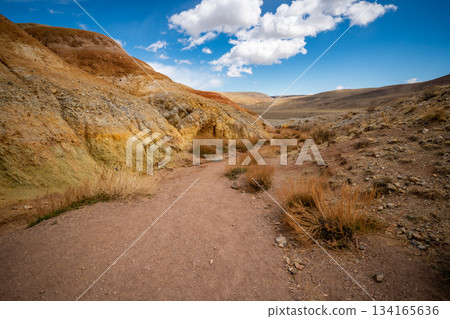 Panoramic view of red and yellow mountains with canyons and gorges at Mars Altai Russia. Popular tourist destination showcasing unique colorful geological formations. Panoramic view of red and yellow mountains with canyons and gorges at Mars Altai Russia. Popular tourist destination showcasing unique colorful geological formations. 134165636