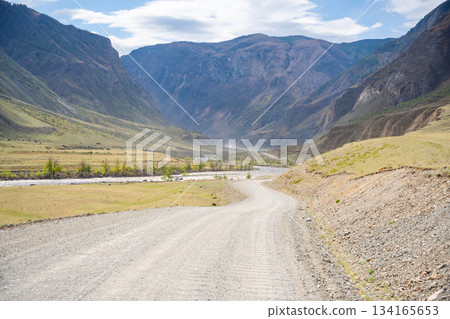 Gravel road running along Chulyshman river in mountain valley Altai Russia Remote travel route through scenic wilderness 134165653