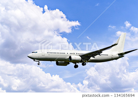 Passenger plane landing at the airport, under a blue sky with white clouds Passenger plane landing at the airport, under a blue sky with white clouds 134165694