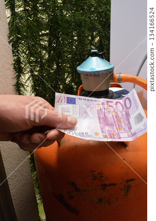 Close-up of a man holding money to buy a gas cylinder. Concept: Subsidized gas shortages in Europe, high fuel costs Close-up of a man holding money to buy a gas cylinder. Concept: Subsidized gas shortages in Europe, high fuel costs 134166524