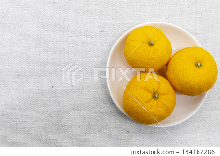 迎接冬至:白色盤子上放著三個柚子,背景是布料。 迎接冬至:白色盤子上放著三個柚子,背景是布料。 134167286