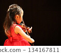 音樂素材，內容為一位穿著紅裙的女孩演奏小提琴及演奏會場景。留有文字空間。 134167811