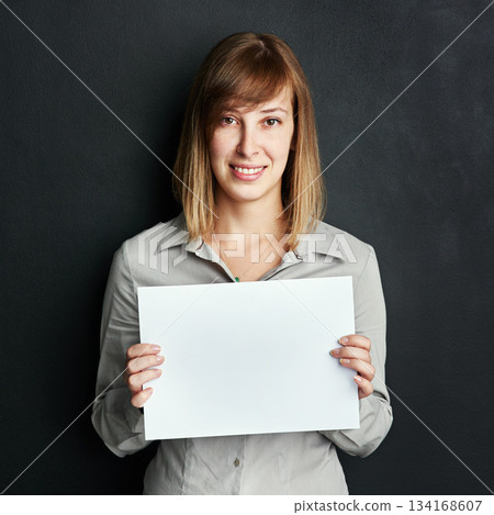 Portrait, poster and mock up with a woman in studio on a dark background holding a blank sign. Announcement, information or advertising with a female brand ambassador showing empty space on a placard 134168607