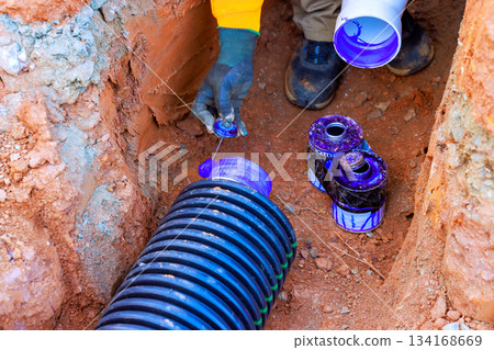 Worker installs drainage pipe in construction site materials on ground 134168669