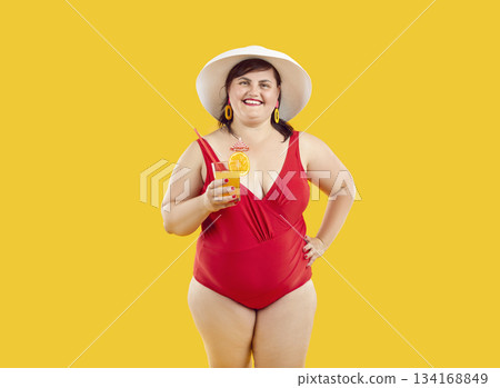 Fat woman in red swimsuit and beach hat holding cocktail isolated on yellow background. 134168849