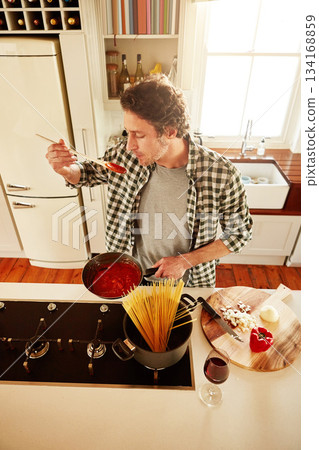 Food, cooking or man tasting in kitchen with healthy vegan diet for nutrition or vegetables at home in Italy. Spaghetti sauce taste, above or person in house kitchen in preparation for dinner meal Food, cooking or man tasting in kitchen with healthy vegan diet for nutrition or vegetables at home in Italy. Spaghetti sauce taste, above or person in house kitchen in preparation for dinner meal 134168859