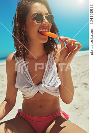 Ice cream eating, beach and woman portrait on holiday by the sea and blue sky with happiness. Sun, sand and young female person face with a smile and lens flare by the ocean in summer on vacation 134168958