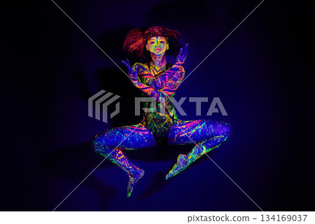 Body paint, dance and portrait of a woman in neon lighting isolated on a dark background in a studio. Creative, glow and a dancing model with psychedelic art for creativity and fluorescent abstract Body paint, dance and portrait of a woman in neon lighting isolated on a dark background in a studio. Creative, glow and a dancing model with psychedelic art for creativity and fluorescent abstract 134169037