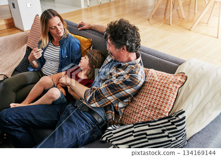 Mom, dad and kid relax on couch in living room for love, care and quality time together in happy family home. Young boy, child and loving parents in lounge for support, bonding and happiness on sofa Mom, dad and kid relax on couch in living room for love, care and quality time together in happy family home. Young boy, child and loving parents in lounge for support, bonding and happiness on sofa 134169144