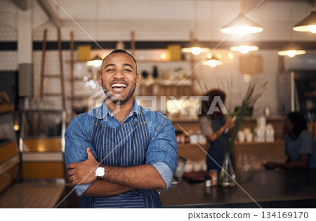 Coffee shop, waiter and portrait of black man laugh in restaurant for cafe service, working and crossed arms. Small business owner, bistro startup and happy male barista in cafeteria ready to serve 134169170