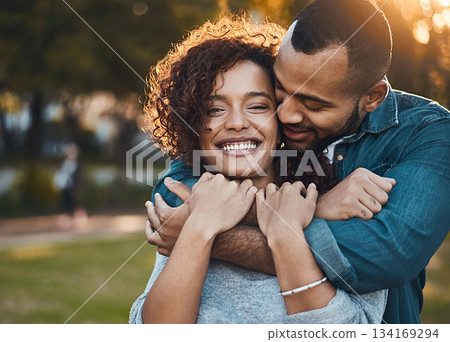Love, hug and couple in park, smile and joy with romance, bonding and relationship with happiness. Portrait, partners or man with woman, embrace, outside or marriage with wellness, loving or carefree 134169294